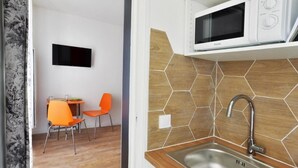 Une cuisine compacte équipée d’un four à micro-ondes, d’un évier et de chaises orange.