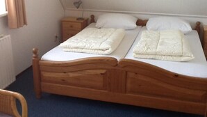 Un letto matrimoniale con testiera e pediera in legno, due comodini e una sedia.