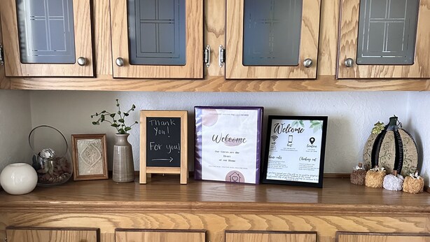 A wooden cabinet with glass doors and metal handles, displaying framed welcome signs and certificates.