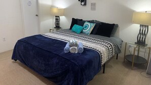 A neatly arranged bedroom with a bed, two bedside lamps, a wall clock, and a family rules sign.