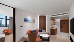 A modern hotel room with a sofa, armchair, and coffee table. There is a painting on the wall, a window with curtains, and a door leading to another room. - Days Inn by Wyndham Hangzhou Gongshu (Hangzhou)