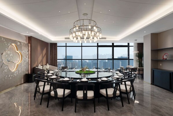 A modern dining room with a round table set for eight, surrounded by chairs.