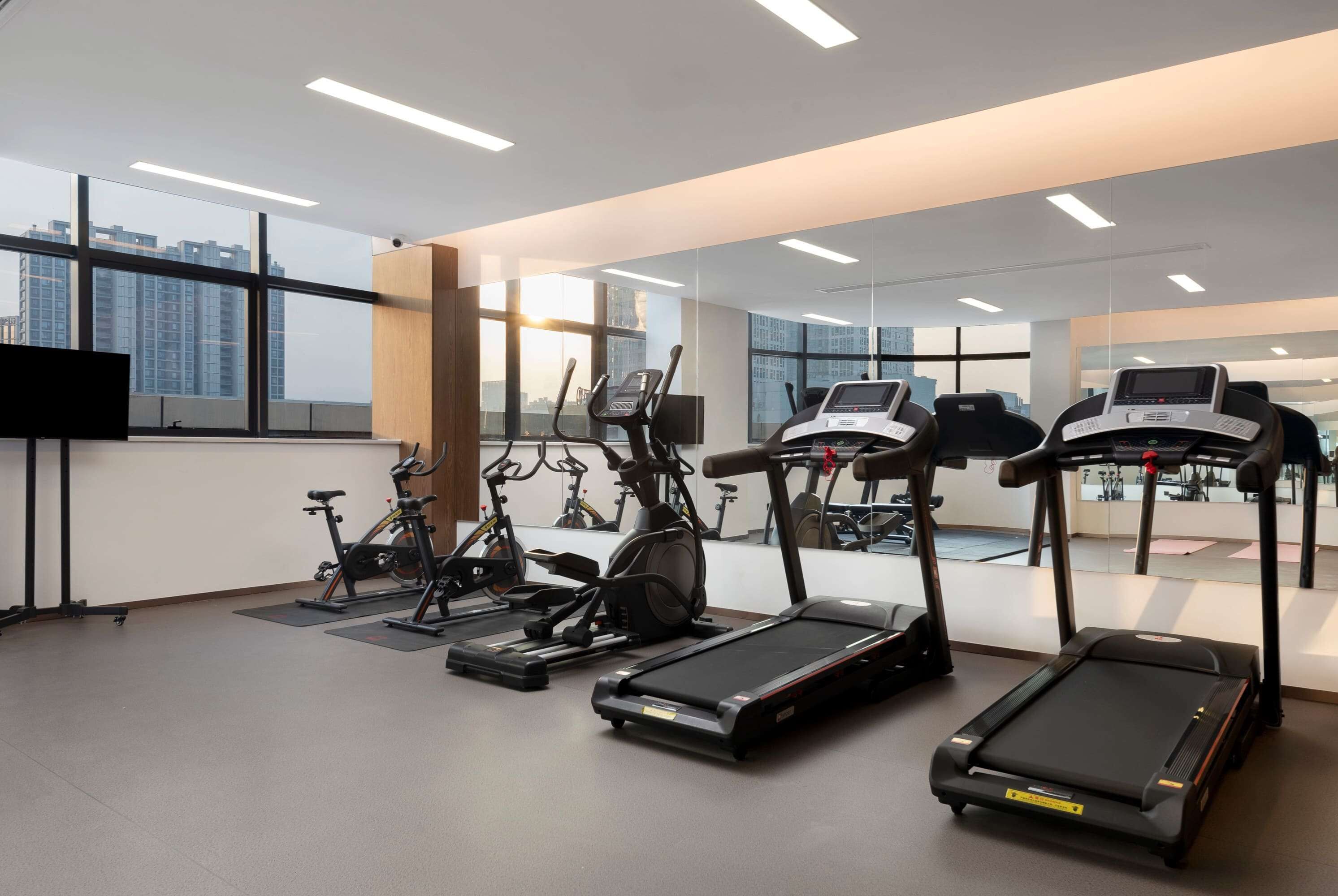 A modern gym with treadmills, stationary bikes, and elliptical machines.