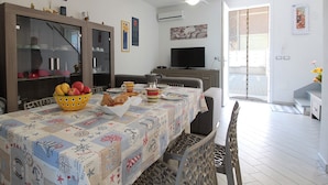 A dining area with a table set for four, a television, and a sliding glass door leading to a balcony. - Villetta Elena, Ac, Wifi, Lido Degli Scacchi (Comacchio)