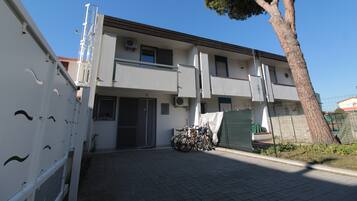 A two-story building with a paved driveway and a bicycle parked outside.