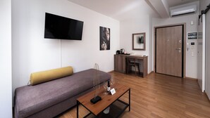 A modern living room with a sofa, a coffee table, a flat-screen TV, and a wooden door.