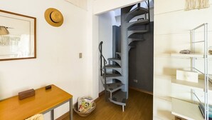A modern interior with a wooden table, a framed picture, a woven hat, a staircase, and a macrame wall hanging. - Charme na Granja - Condomínio (Carapicuiba)