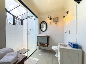A modern bathroom with a glass shower enclosure, a white sink, a toilet, and a vanity with a mirror. - Charme na Granja - Condomínio (Carapicuiba)