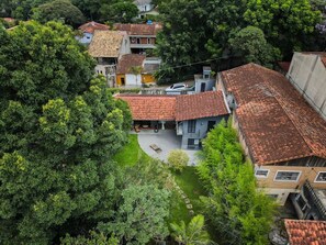 A residential area with terracotta-tiled roofs, surrounded by lush greenery. - Charme na Granja - Condomínio (Carapicuiba)