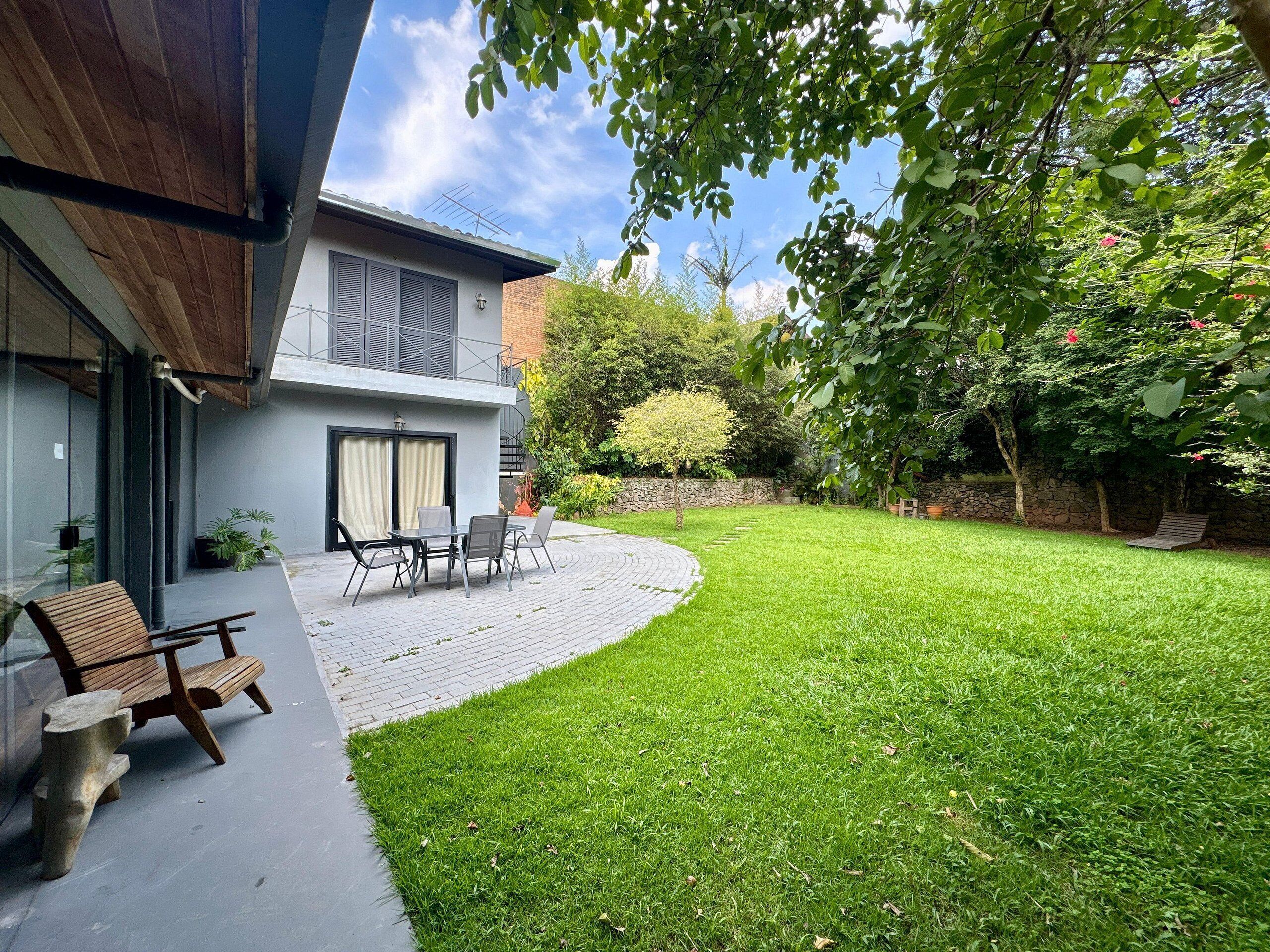 A modern house with a patio, a wooden bench, and a table.