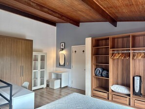 A room with a wooden wardrobe, a desk, a chair, and a bed with a patterned bedspread. - Charme na Granja - Condomínio (Carapicuiba)