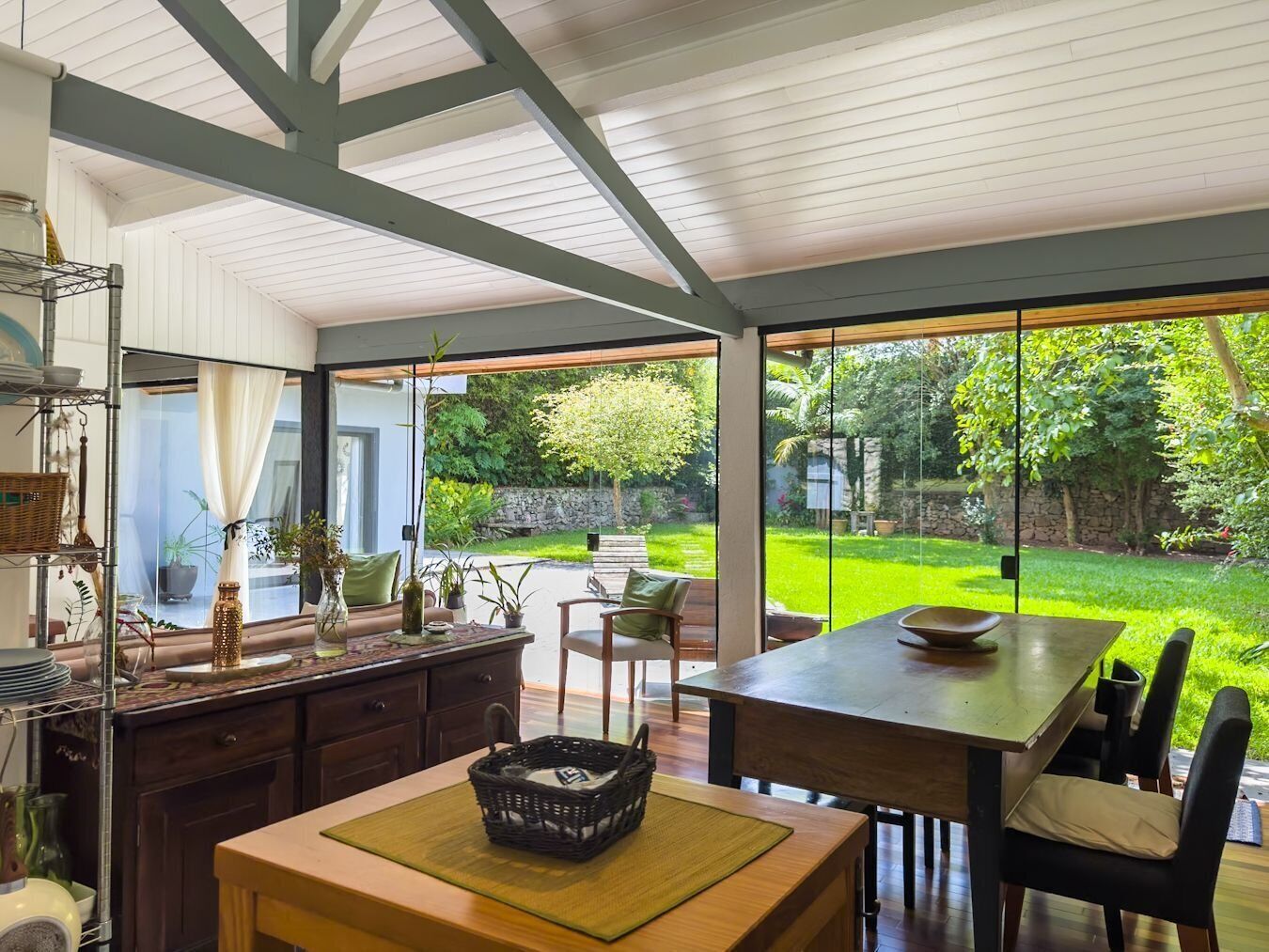 Une cuisine moderne avec un coin repas, de grandes fenêtres et une vue sur le jardin.