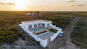 Una casa moderna con piscina, circondata da un recinto bianco, immersa nella campagna.