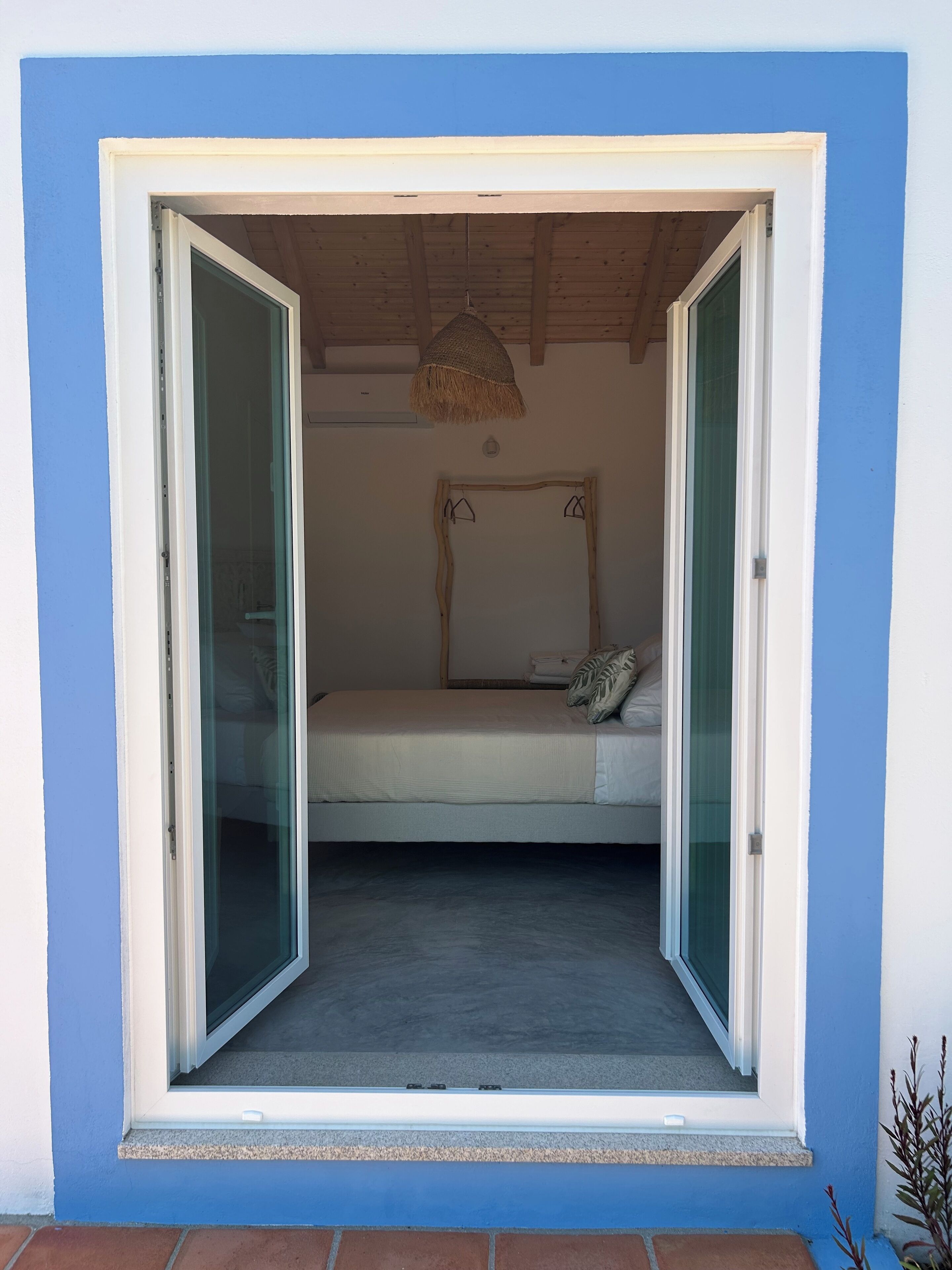 A bedroom with a bed, a hanging light fixture, and a window.