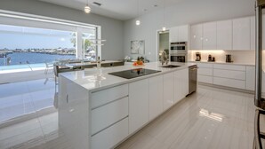 Una cocina moderna con una isla grande, armarios blancos y vistas al agua.