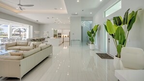 Una sala de estar moderna con un sofá grande, una zona de comedor y una cocina al fondo.