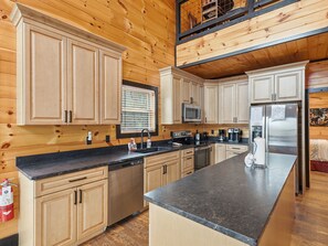 Eine moderne Küche mit Holzausstattung, einem Edelstahlkühlschrank und einer eingebauten Mikrowelle.