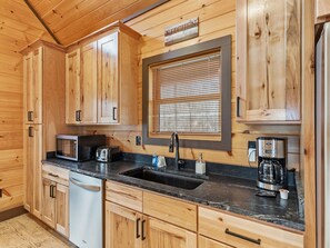 A wooden kitchen with a built-in microwave, toaster, sink, and coffee maker.
