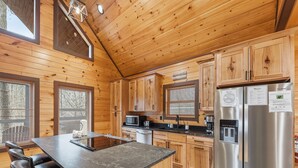 A modern kitchen with wooden cabinetry, a stainless steel refrigerator, and a central island with seating.
