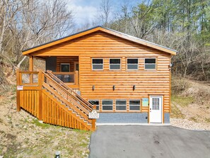Une cabane en rondins avec un escalier menant à une terrasse, de nombreuses fenêtres et une porte.