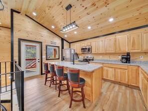 A modern kitchen with wooden cabinets, a granite countertop, and a stainless steel refrigerator. - Luxury Cabin w/Huge Game Room, Fire Pit & Hot Tub (Pigeon Forge)