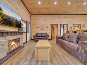Un intérieur chaleureux avec des boiseries, une cheminée, des canapés en cuir et un plancher en bois.