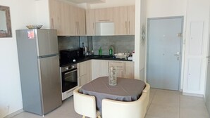 A compact kitchen with a refrigerator, oven, microwave, and a small dining table with a chair. - Alpes maritimes front de mer cagnes sur mer  (Cagnes-sur-Mer)