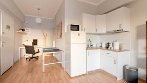 A compact kitchen with white cabinets, a microwave, a sink, and a trash bin. - Athenian Entertainment Relaxation Hub (Athens)