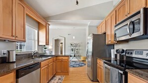 A modern kitchen with wooden cabinets, stainless steel appliances, and a granite countertop. - Waterview 3 Bed In Sunridge Woods 3 Bedroom Villa (Davenport)