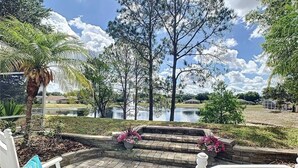 A patio area with a view of a lake and trees. - Waterview 3 Bed In Sunridge Woods 3 Bedroom Villa (Davenport)