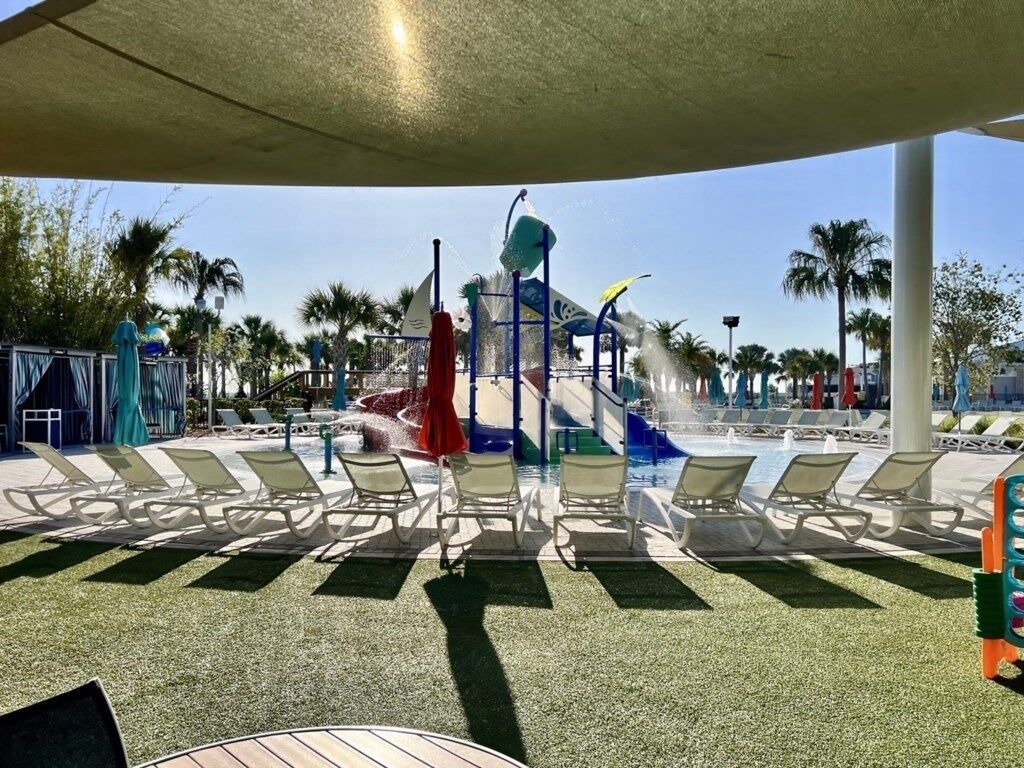 A water park with a water slide, lounge chairs, and palm trees.