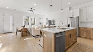 A modern kitchen with a central island, wooden cabinets, and stainless steel appliances. - Villa #30 At Bloomington Country Club - Red Cliffs 4 Bedroom Townhouse (St. George)