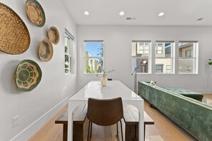 A modern dining area with a white table, brown chairs, and a green sofa. - Villa #11 Adventure Retreat At Bloomington Villas 4 Bedroom Townhouse (St. George)