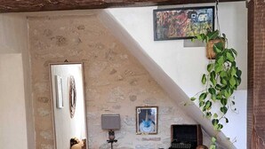Ein rustikaler Raum mit einem Holzkabinett, einem Spiegel, einem Schreibtisch mit Lampe und einer hängenden Pflanze.
