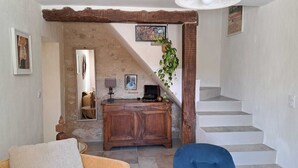 Ein Zimmer mit Steinsandsteinwand, einem Holztisch mit Lampe, einem Spiegel und einem blauen Stuhl sowie einer Treppe.