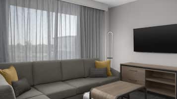 Una sala de estar moderna con un sofá modular, un escritorio de madera y un televisor de pantalla plana montado en la pared.