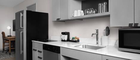 A modern kitchen with a refrigerator, dishwasher, microwave, and a coffee maker on the counter.