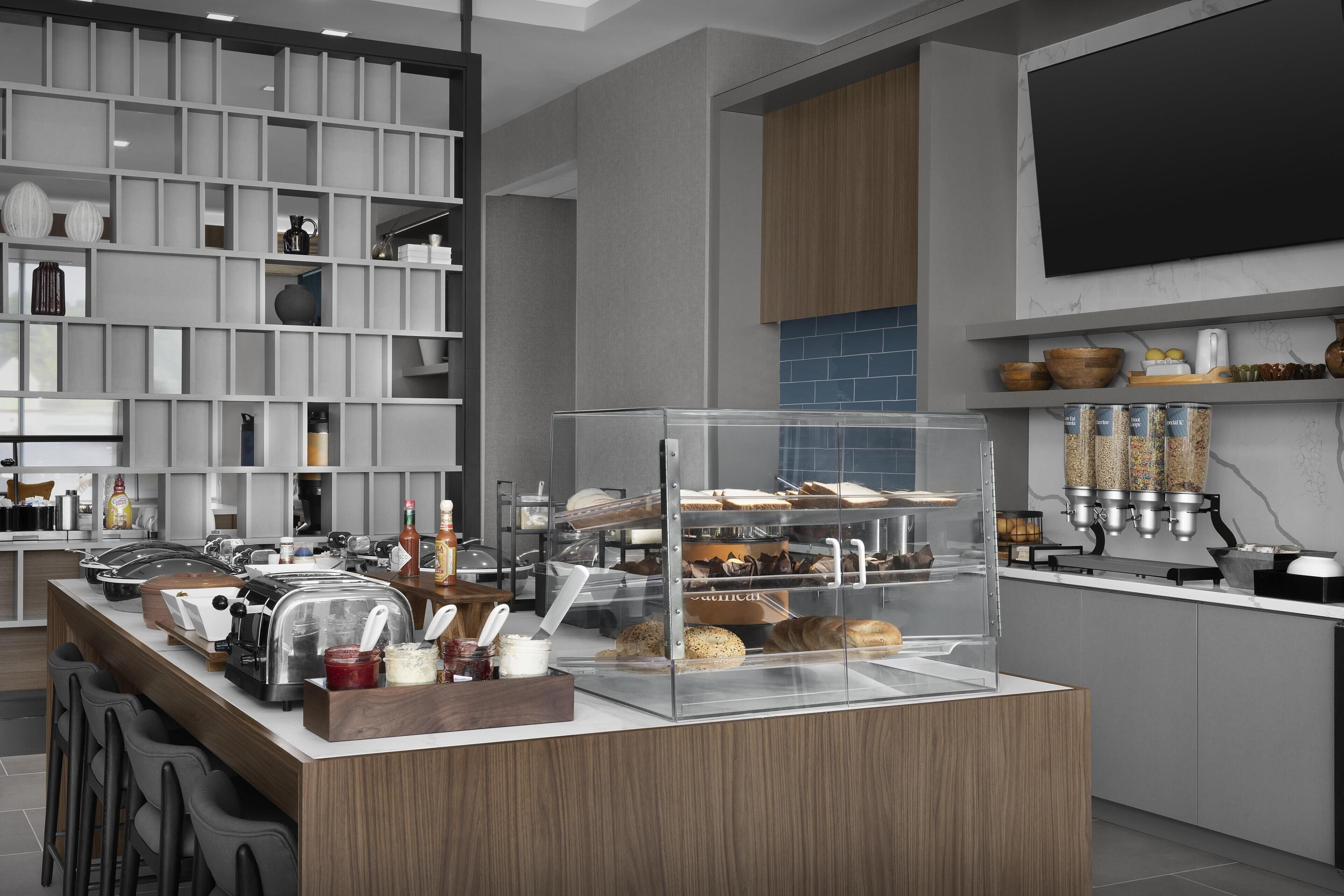 A modern kitchen with a central island, built-in shelves, and a variety of appliances and food items.