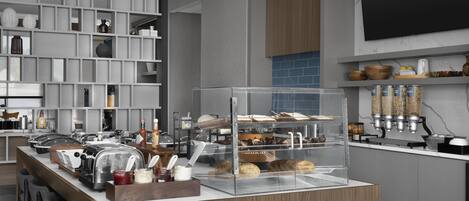 A modern kitchen with a central island, built-in shelves, and a variety of appliances and food items.