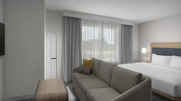 A hotel room with a bed, a sofa, a small table, and a TV.