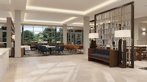 A modern hotel lobby with a seating area, a reception desk, and a large window offering a view of the outdoors. - Homewood Suites by Hilton Jackson (Jackson)