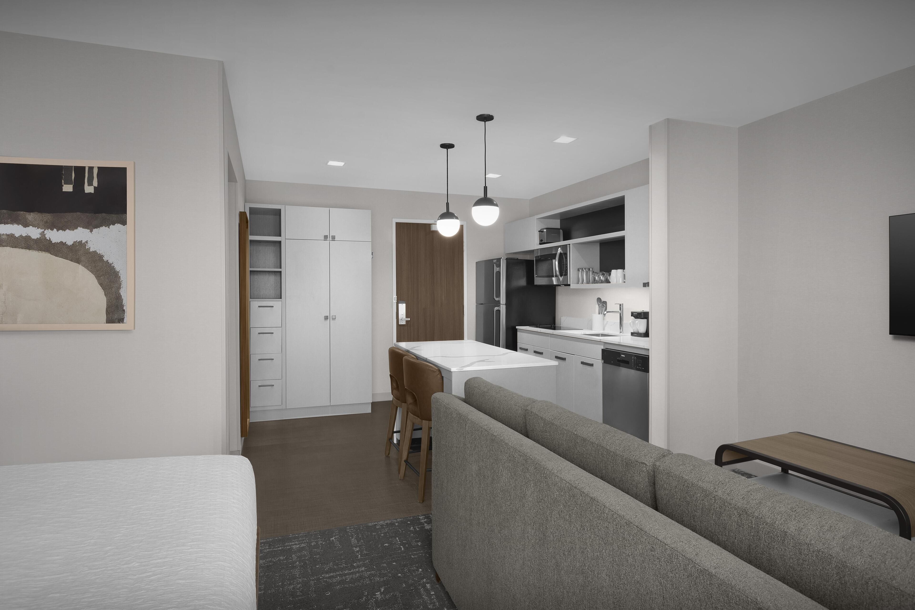 A modern, compact living space with a kitchenette, a dining area, and a sofa.