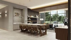 A modern kitchen with a central island, bar stools, and a built-in coffee machine. - Homewood Suites by Hilton Jackson (Jackson)
