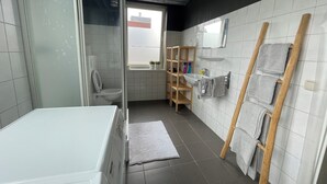 A modern bathroom with a white sink, wooden shelves, a towel rack, and a shower area. - Topsleep Apartments 26-1 (Arnhem)