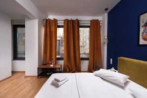 A hotel room with a bed, a desk, and a window with curtains.