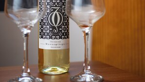 Una botella de vino con etiqueta decorativa y dos copas de vino vacías sobre una superficie de madera.