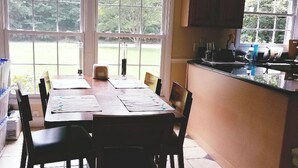 Une cuisine avec une table à manger, des chaises et une fenêtre donnant sur un jardin.