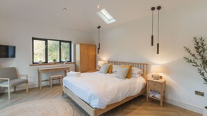 Un dormitorio moderno con una cama grande, un escritorio y un televisor.