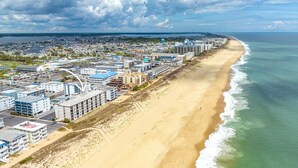 A coastal cityscape with a beachfront hotel, modern buildings, and a clear view of the ocean.