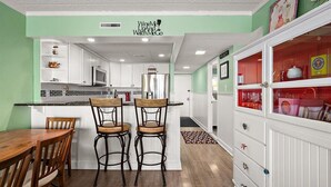 A kitchen with white cabinets, a wooden dining table, and two bar stools.